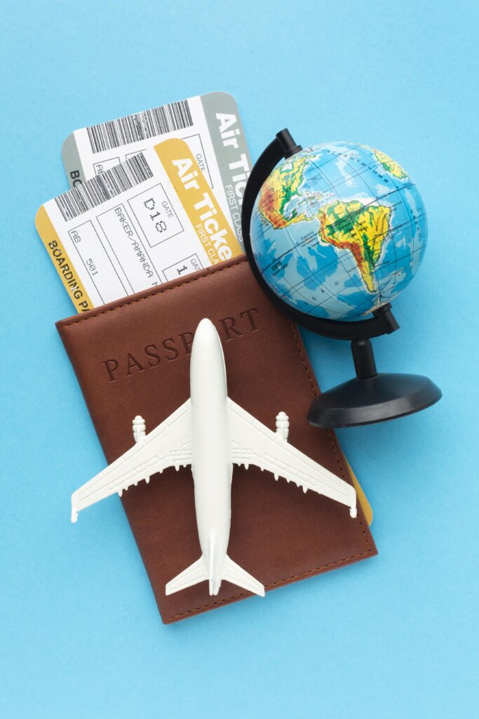 Passport, airplane model, boarding pass, and globe on blue background, symbolizing travel planning and services offered by Tropical Travel Adventures in Elk Grove.