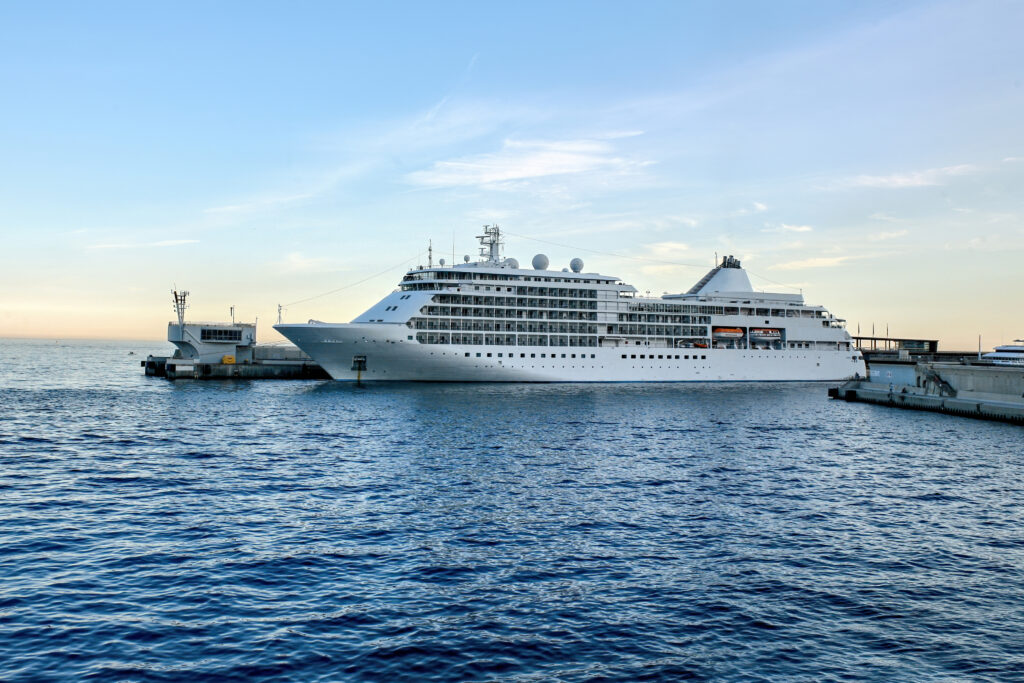 Large cruise ship docked at a harbor with calm waters, representing ocean cruise options for first-time travelers.